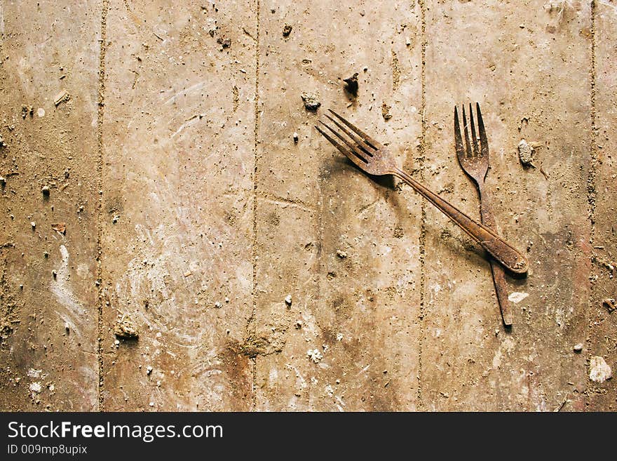 A apir of rusty forks on a dirty wooden floor