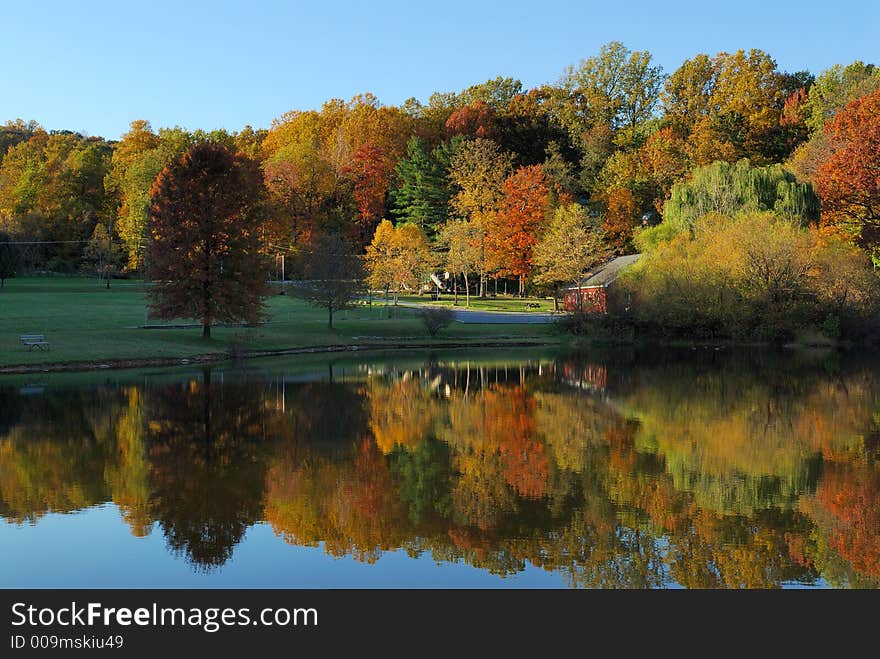 Colorful fall trees and a red building reflected from a lake at a park. Colorful fall trees and a red building reflected from a lake at a park