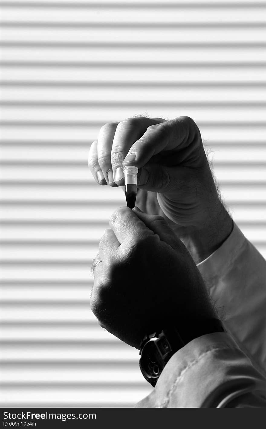 Grayscale close up of hands holding laboratory vial. Grayscale close up of hands holding laboratory vial