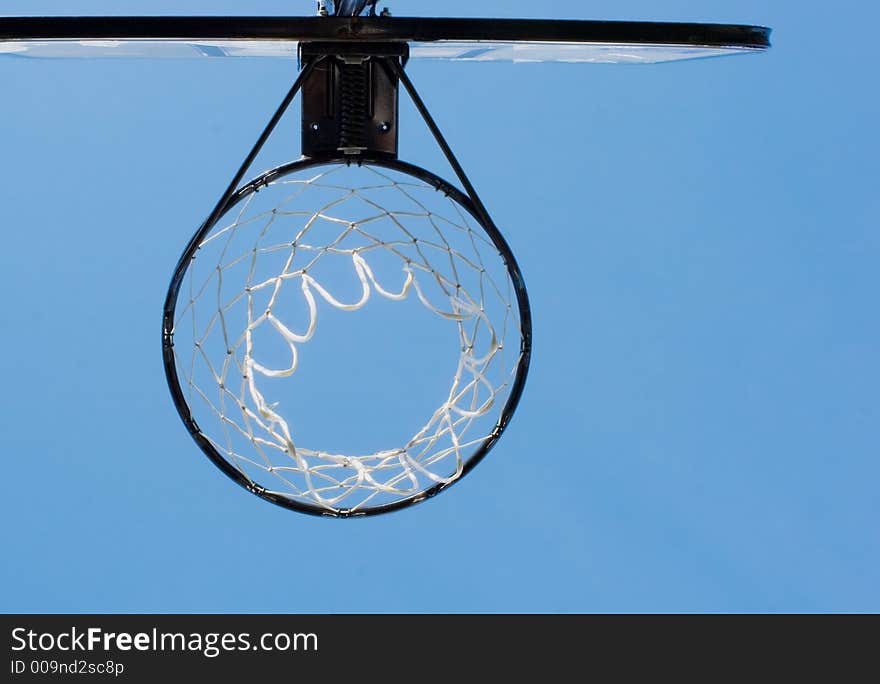 View of a basketball hoop from below, blue sky as a backdrop