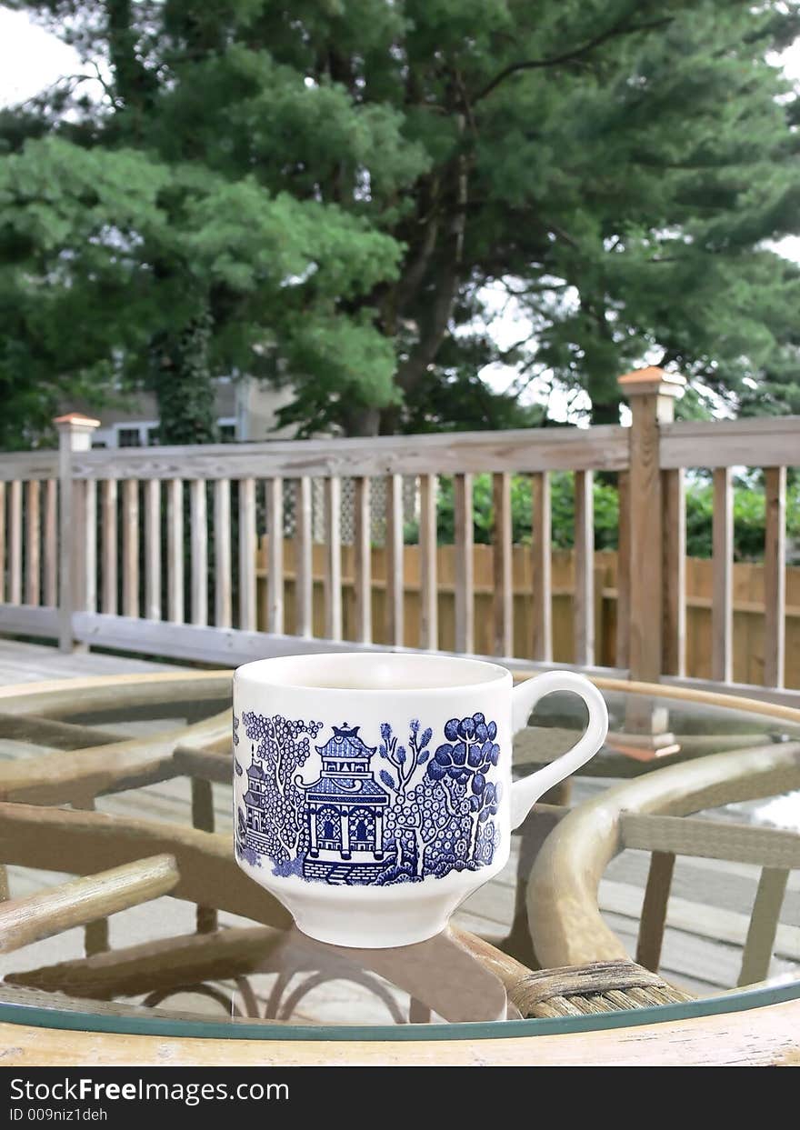 A coffee cup on a glass table on the porch.