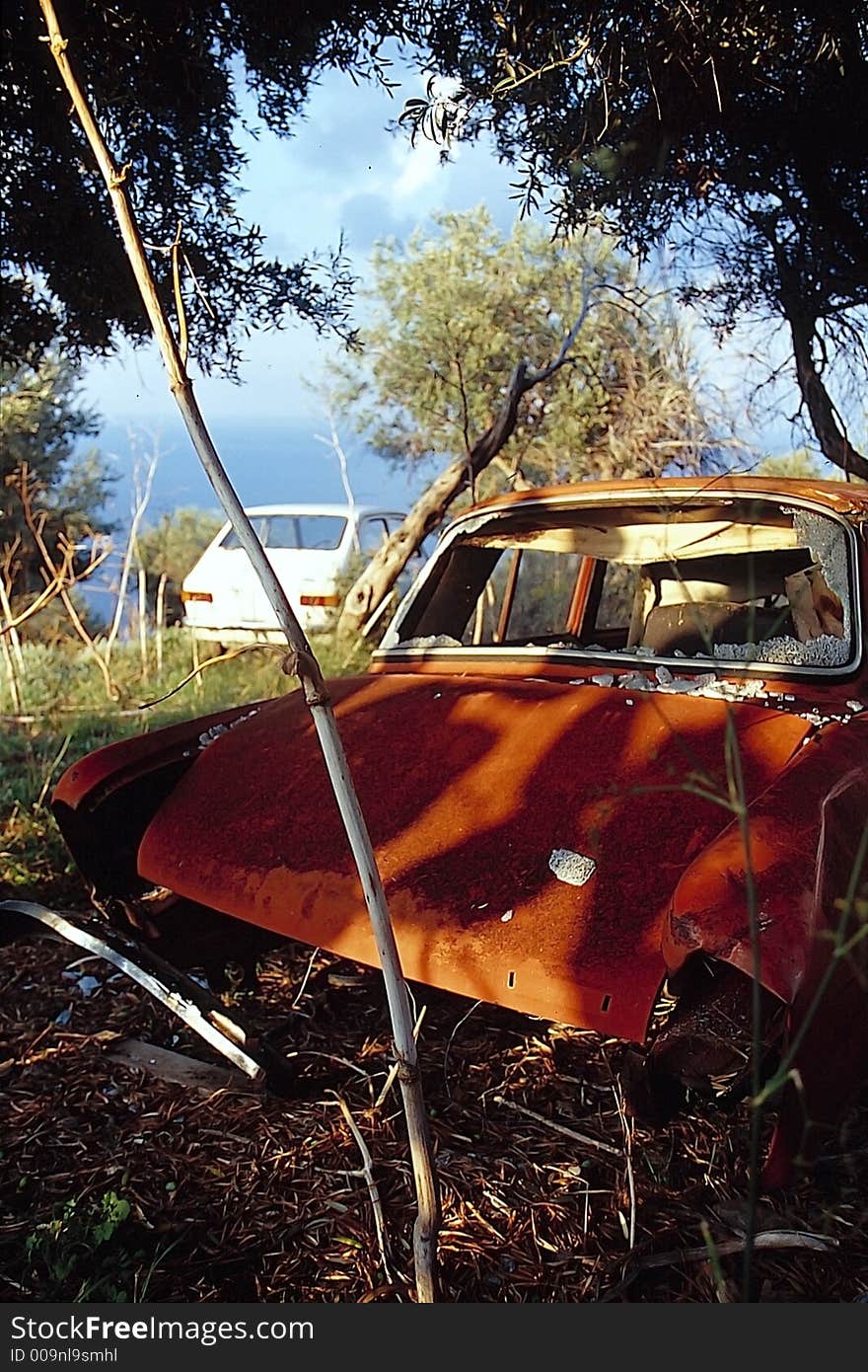 A rusted car in front of the sea