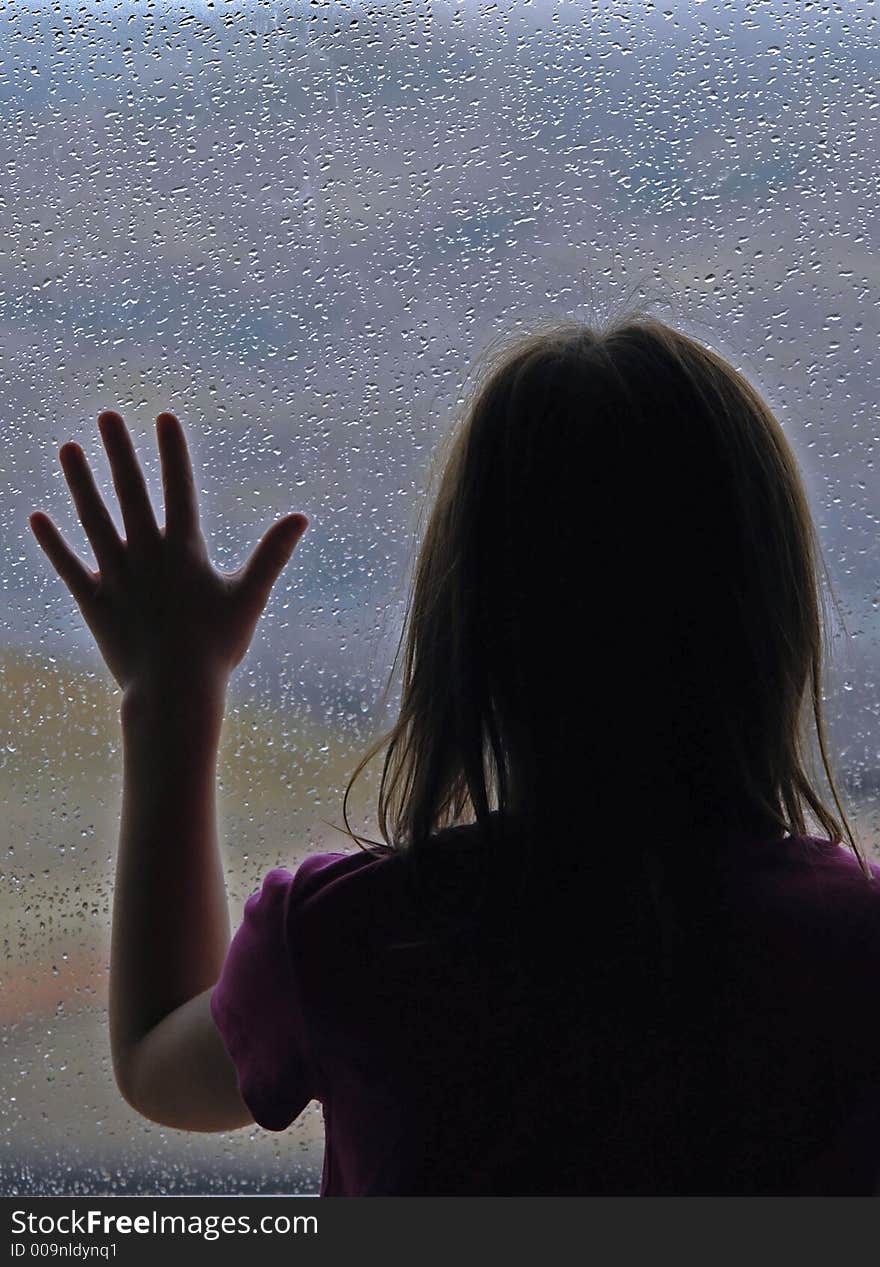 Little girl standing by window with raindrops on it on a rainy day. Little girl standing by window with raindrops on it on a rainy day