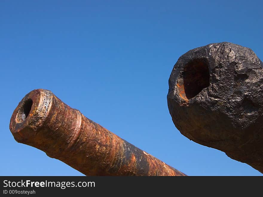 Two old cannon barrels against a clear blue sky. Two old cannon barrels against a clear blue sky