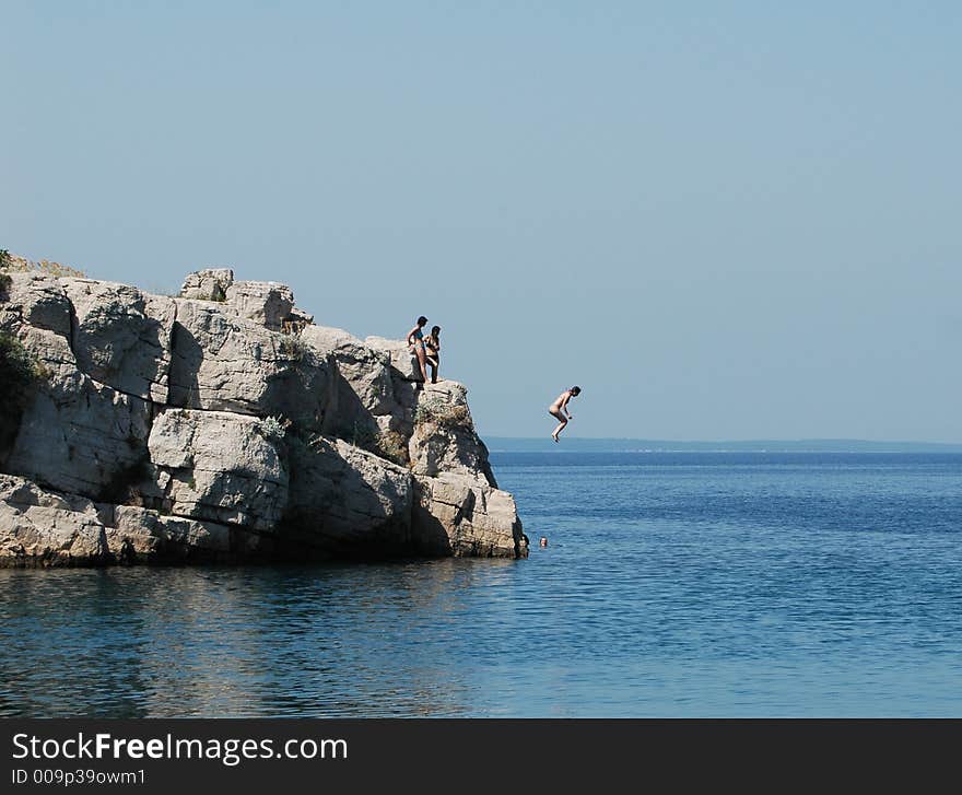 Girl jump from the stone in sea