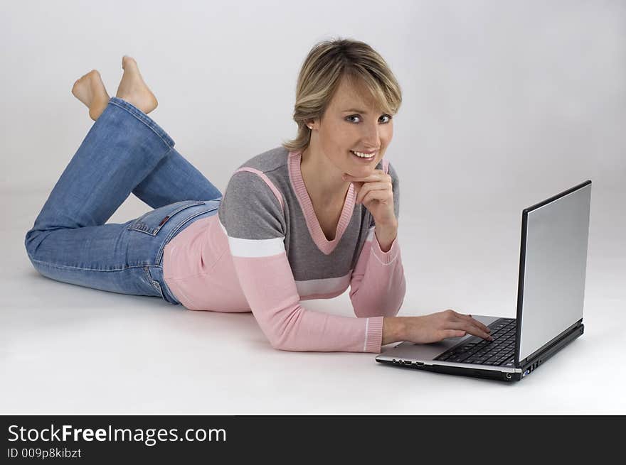 Blondie young girl laying down with laptop on white. Blondie young girl laying down with laptop on white