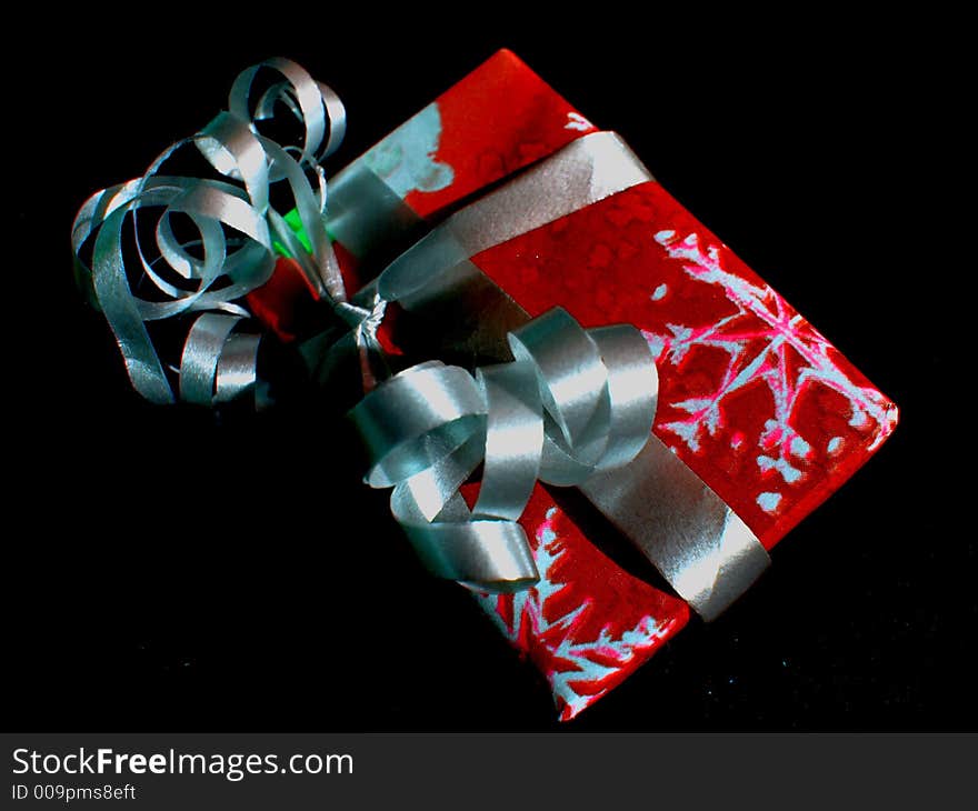 Single Christmas gift boxed and wrapped in red and white with ribbons in twirls. Single Christmas gift boxed and wrapped in red and white with ribbons in twirls