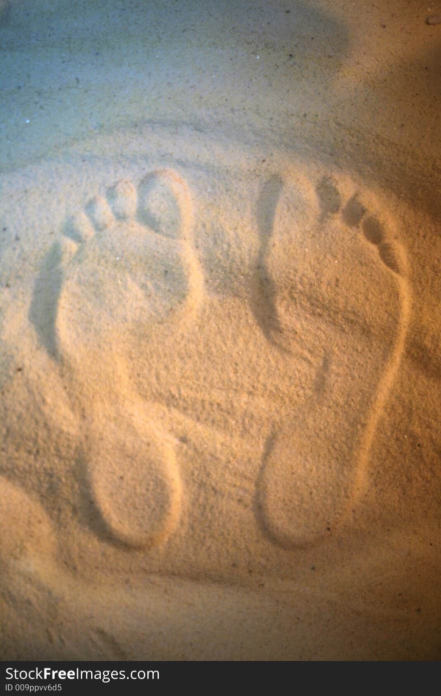 Pair prints of female legs on sand