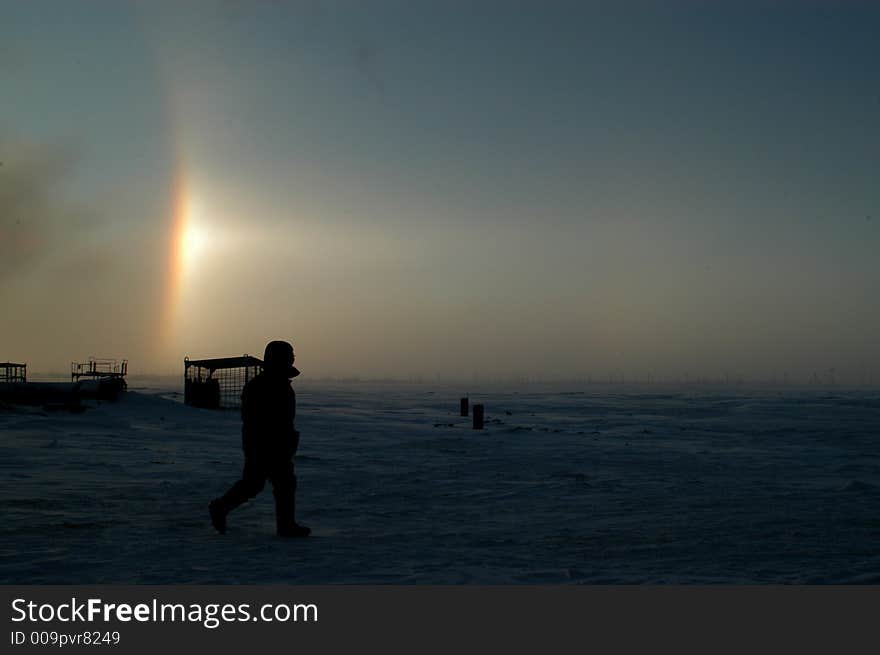 Gas field, winter, a worker walks to the construction site, a wonderful rainbow is on the background. Gas field, winter, a worker walks to the construction site, a wonderful rainbow is on the background.