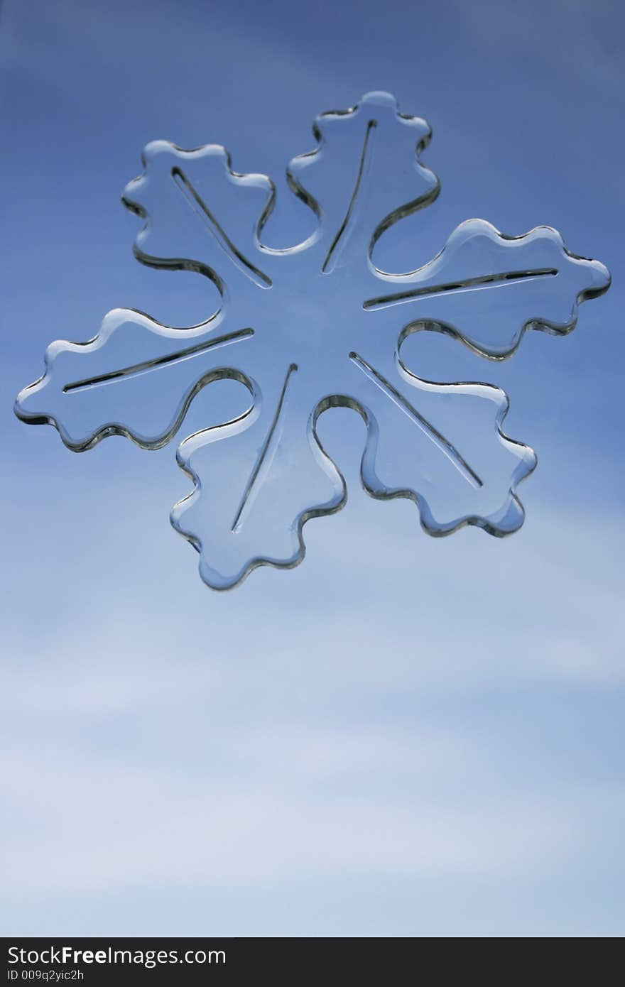 Large snowflake window decal against a soft blue sky