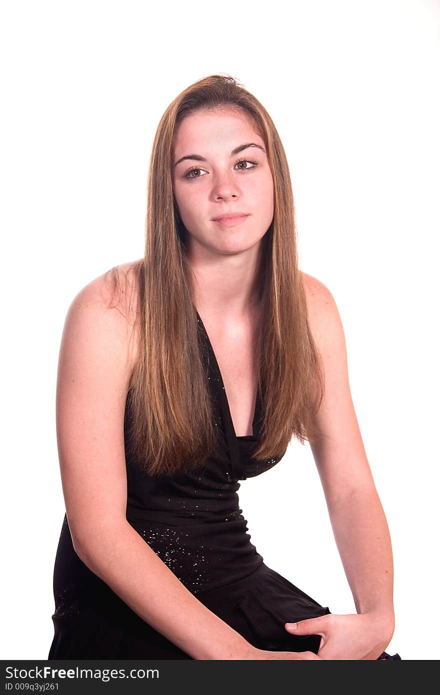 Teen girl in black dress seated with dreamy gaze over white. Teen girl in black dress seated with dreamy gaze over white