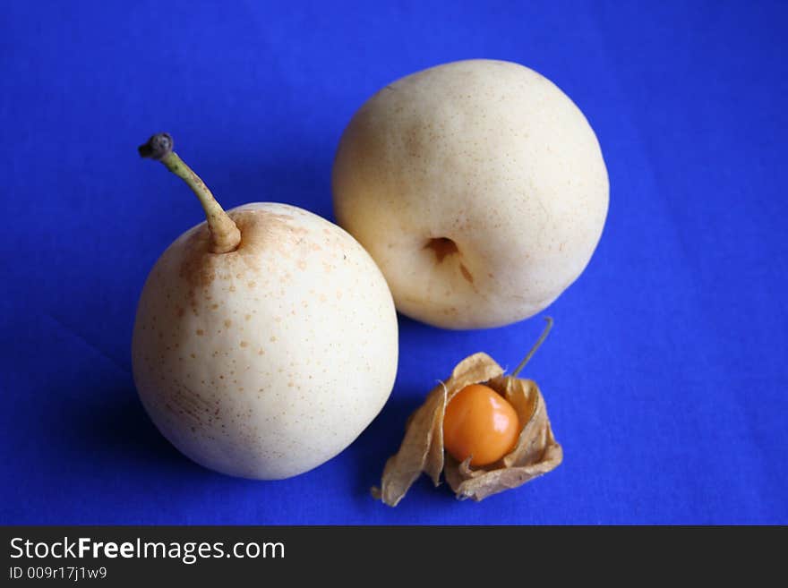 Physalis and nashi pears together against blue background. Physalis and nashi pears together against blue background