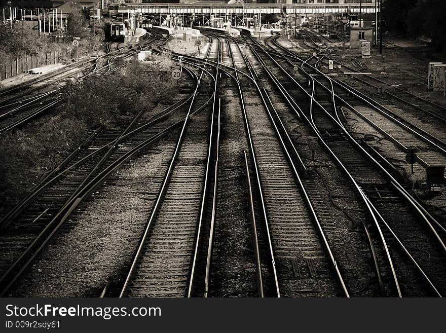 A view down on to a complex series of railway lines and junctions, leading in a major railway station in Guildford, UK. In sepia with subtle vignetting.