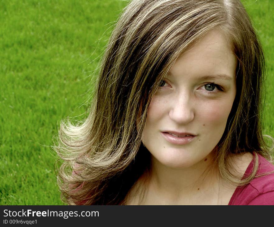 Young girl with serious expression sitting outside in grass. Young girl with serious expression sitting outside in grass