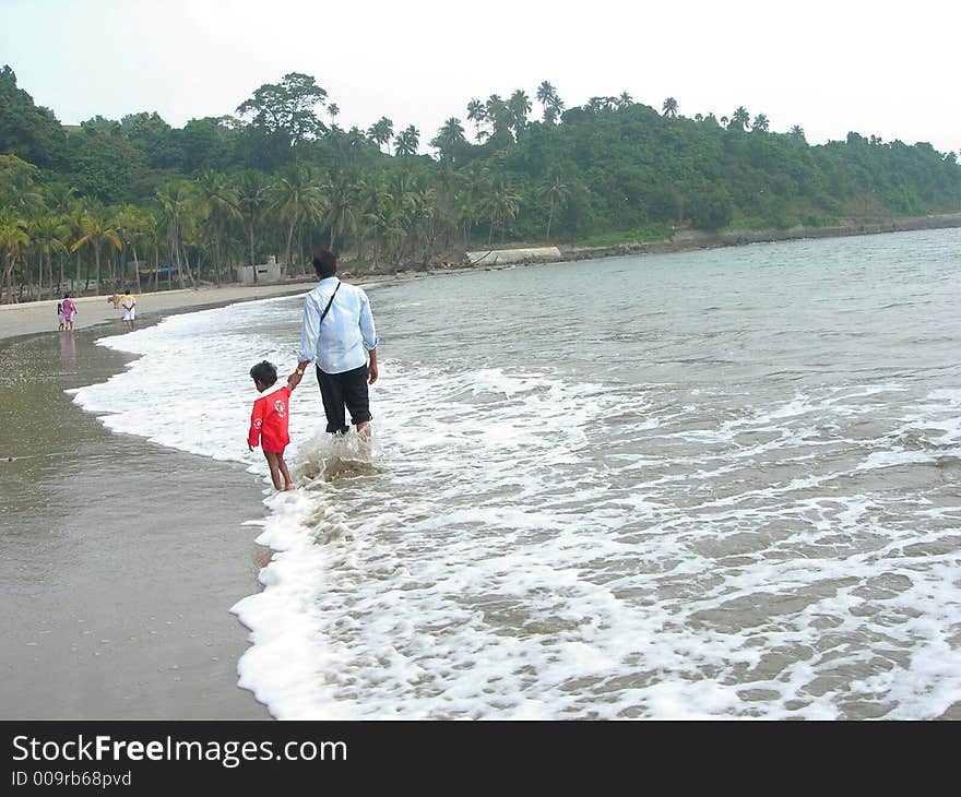 An image showing father and son strolling on a beach. An image showing father and son strolling on a beach