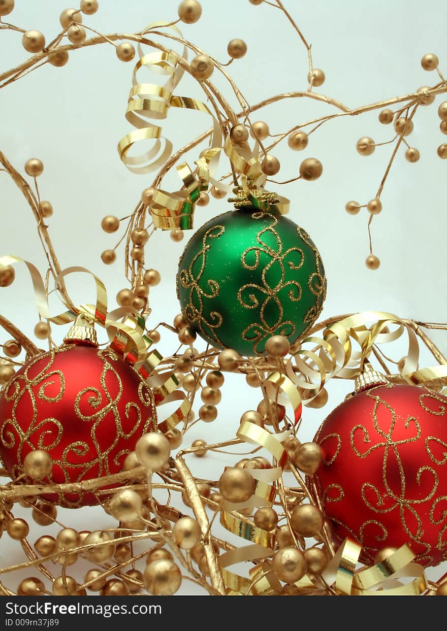 A trio of red and green Christmas ornaments decorated with ribbons and gold berries. A trio of red and green Christmas ornaments decorated with ribbons and gold berries