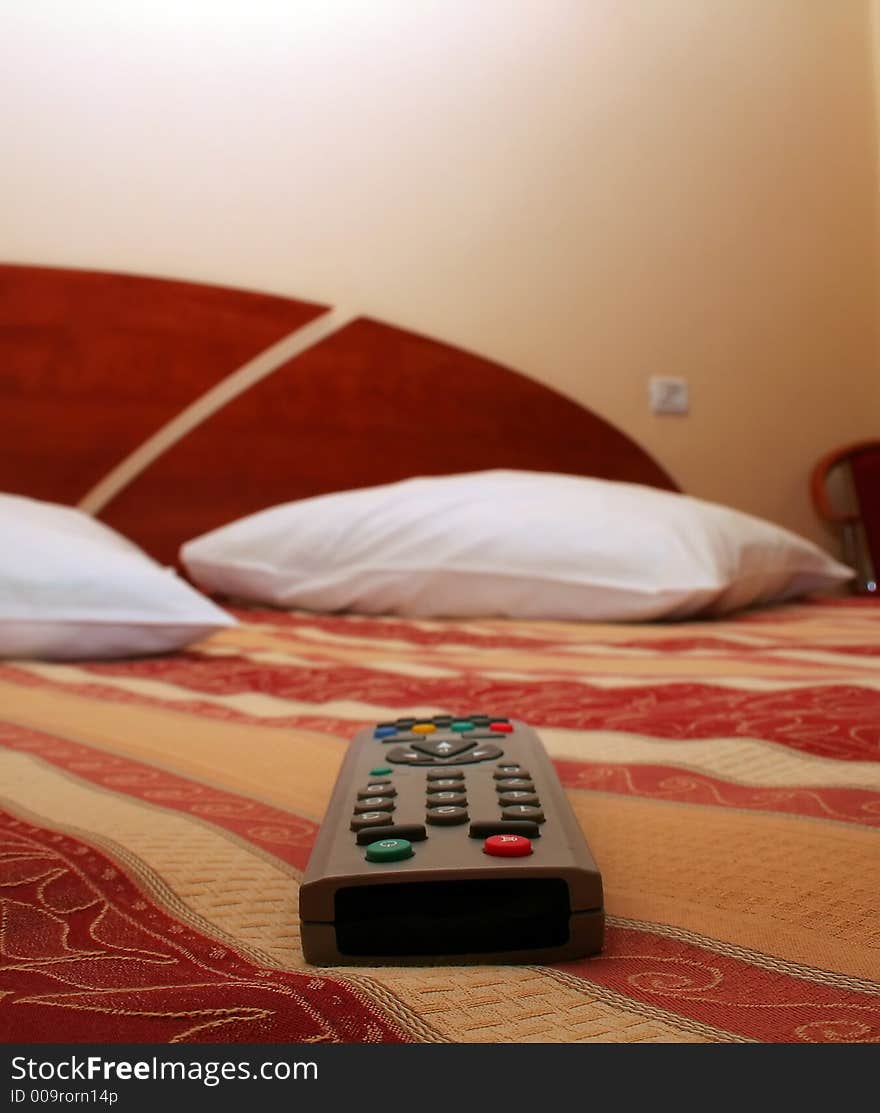 Luxury hotel room decor accommodation with TV remote in front plane, selective focus on remote