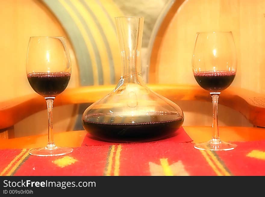 A composition of a bottle of red wine and glass with wine cellar in background. Soft filter added