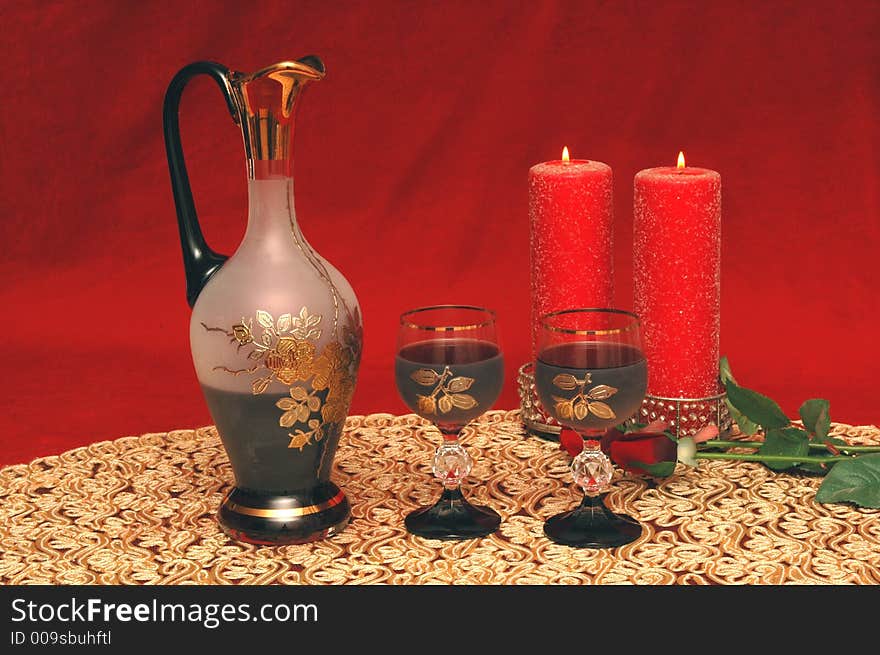 A jug of wine ,glasses and candles