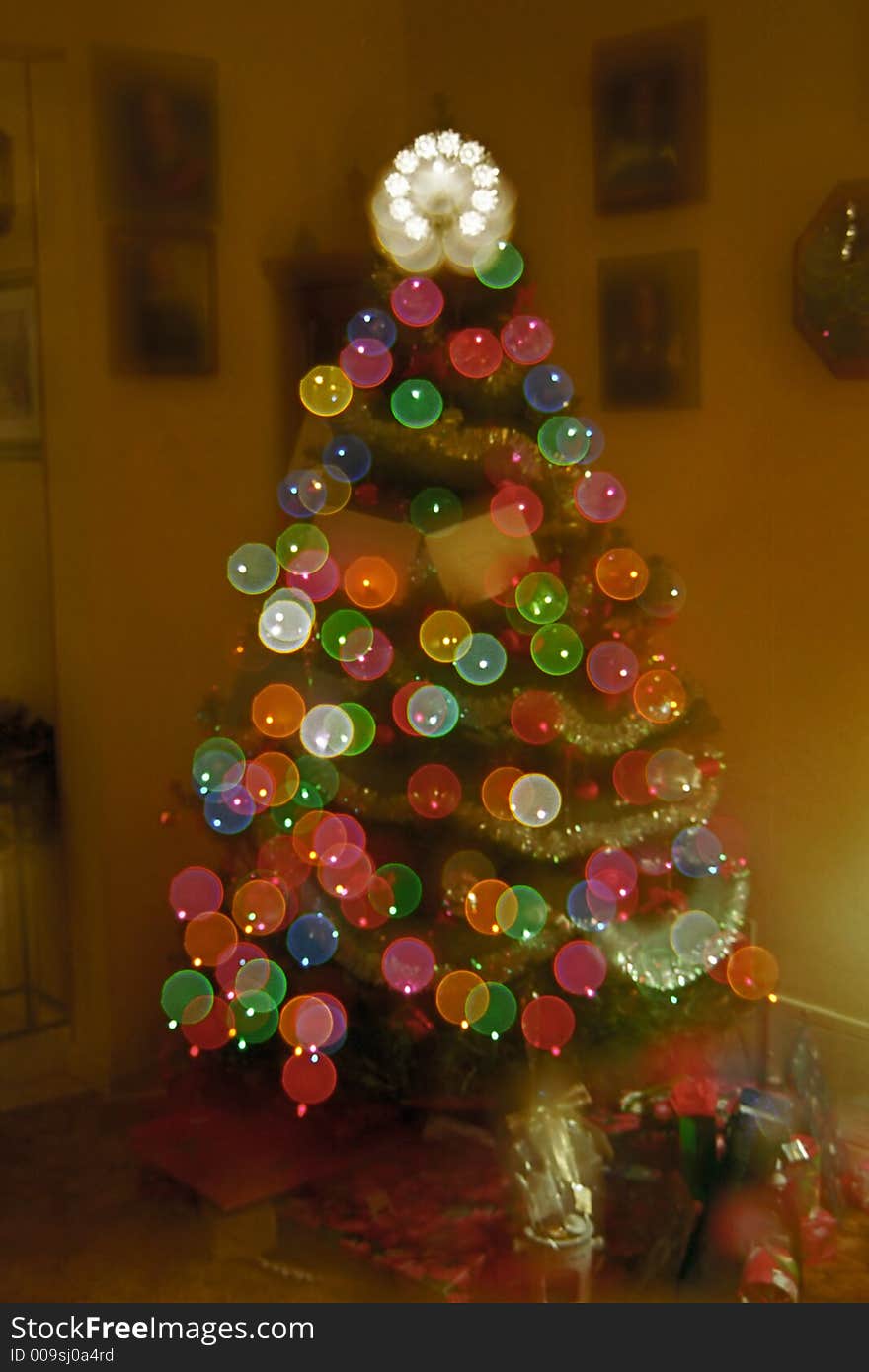 A decorated Christmas tree with gifts in a home living room. Double exposure to provide a flared abstract lighting effect. A decorated Christmas tree with gifts in a home living room. Double exposure to provide a flared abstract lighting effect.