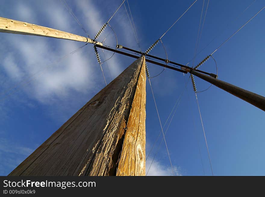 View of power lines from below with blue sky and clouds