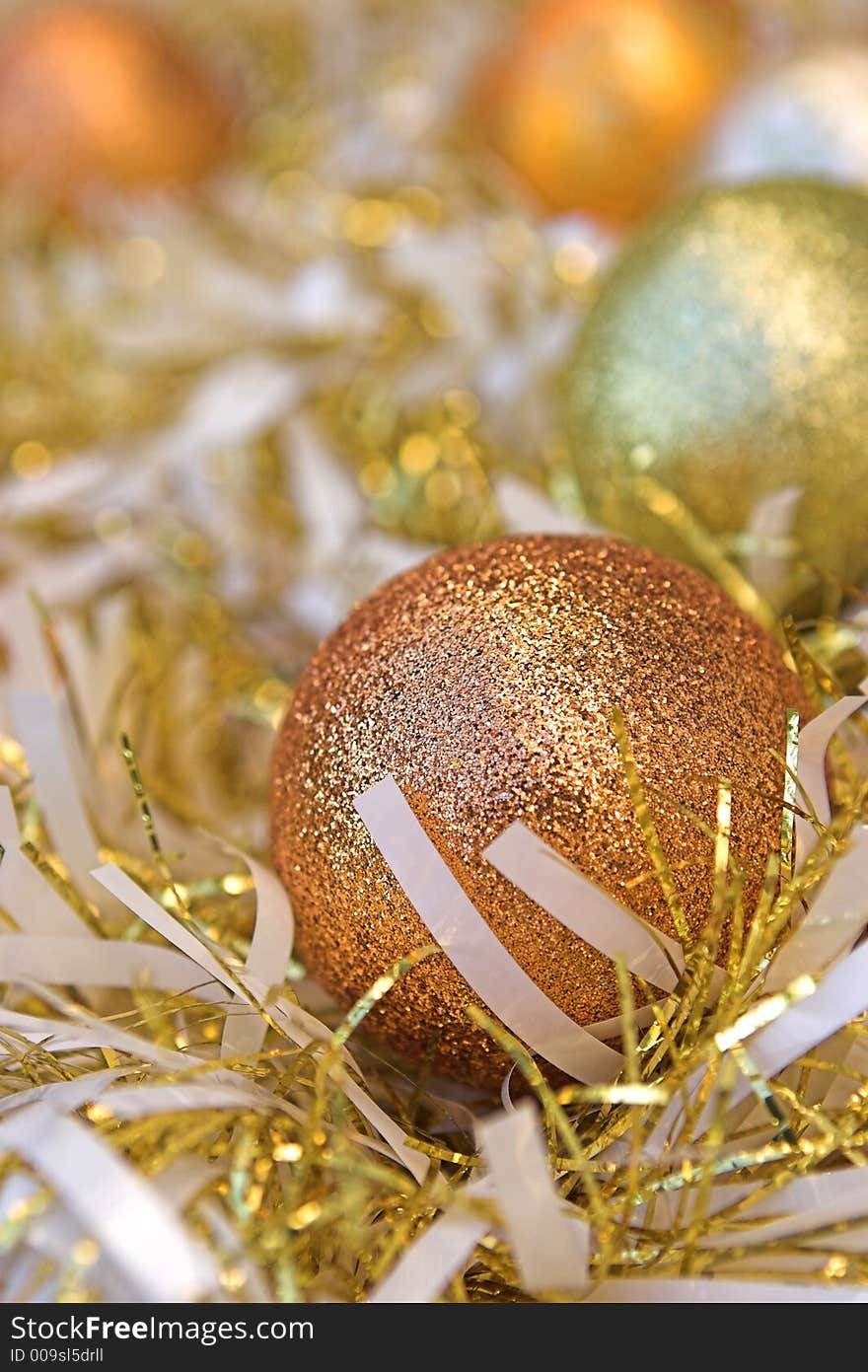 Christmas baubles nestled amongst white & gold tinsel - sublime focus on the closest bauble. Christmas baubles nestled amongst white & gold tinsel - sublime focus on the closest bauble