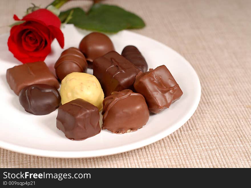 Variety of chocolates and a rose on a white plate