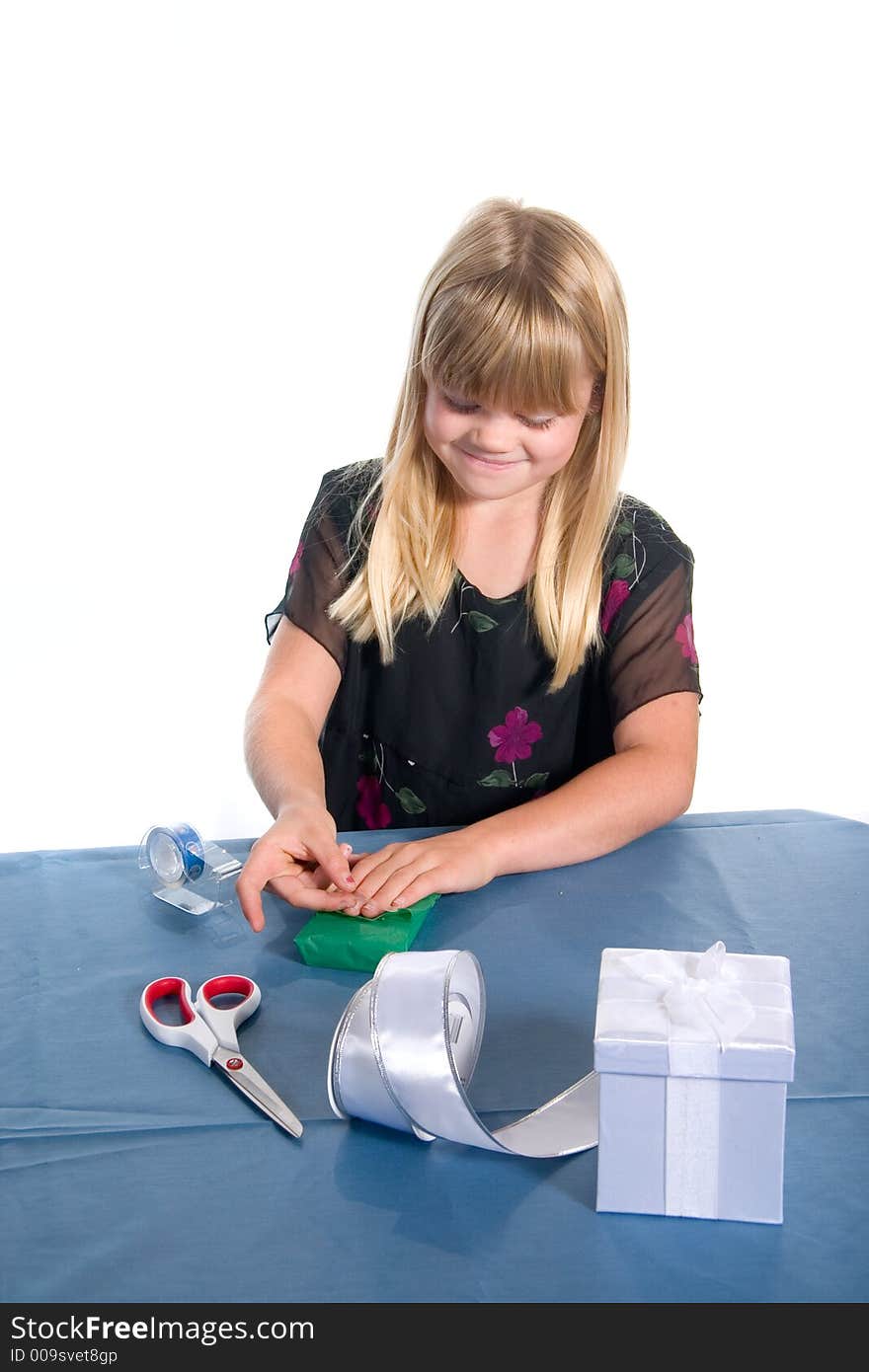 Young girl wrapping green gift at table for christmas. Young girl wrapping green gift at table for christmas