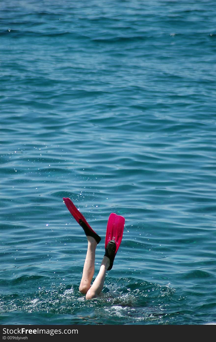 Alone boy diving with fins on the coastline