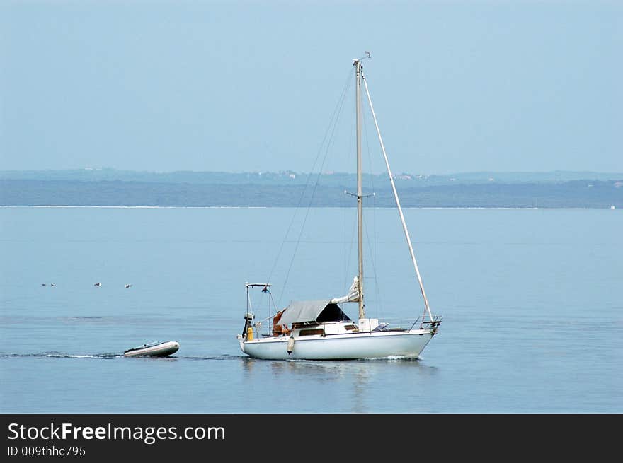 Sail boat and small rescue boat at the open sea