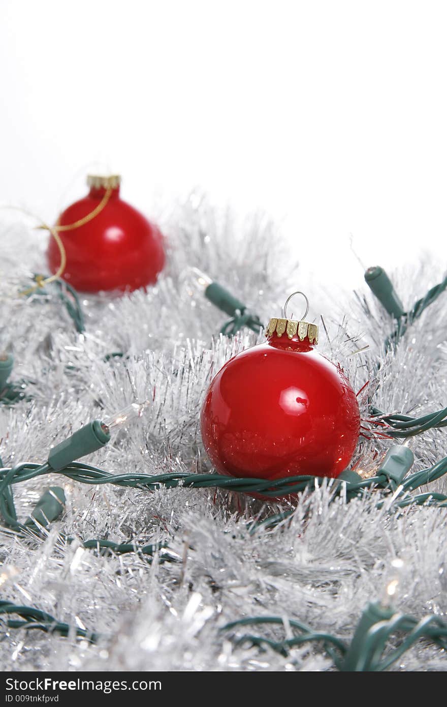 Fancy christmas ornaments in a pile of silver garland with tree lights