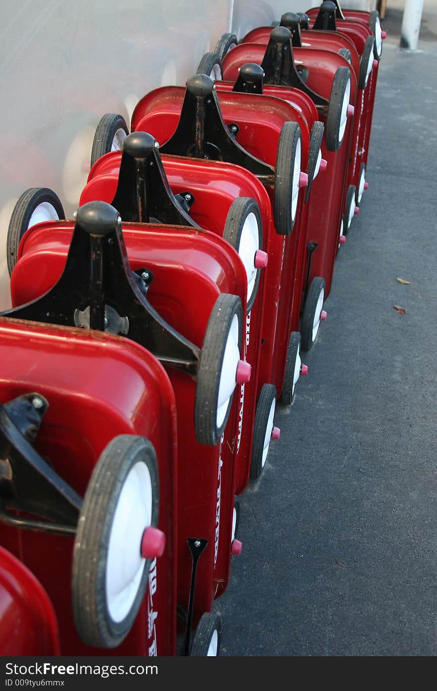 Red wagons and wheels lined up in a row outside