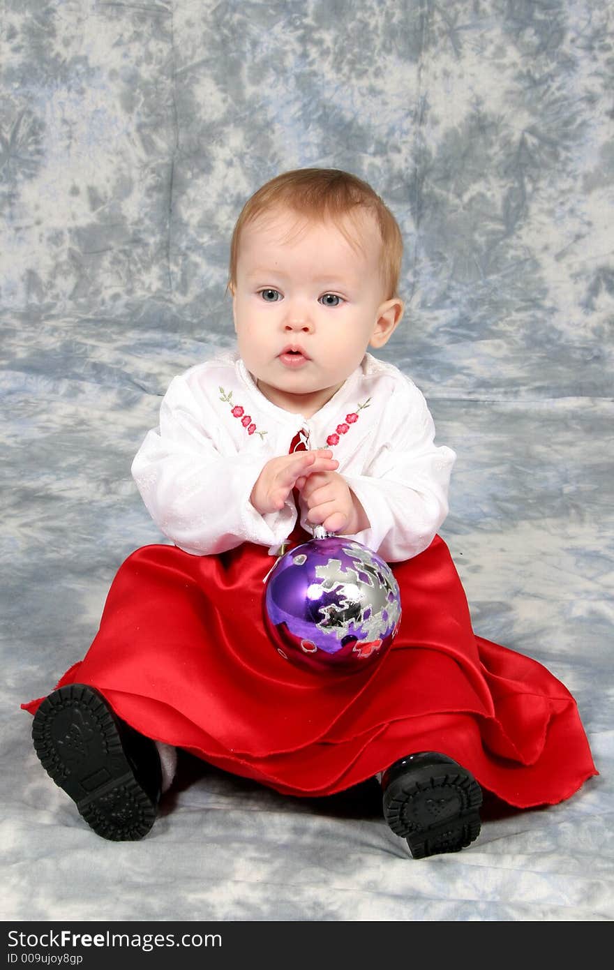 Little Baby Girl in Christmas dress with bulb in hand