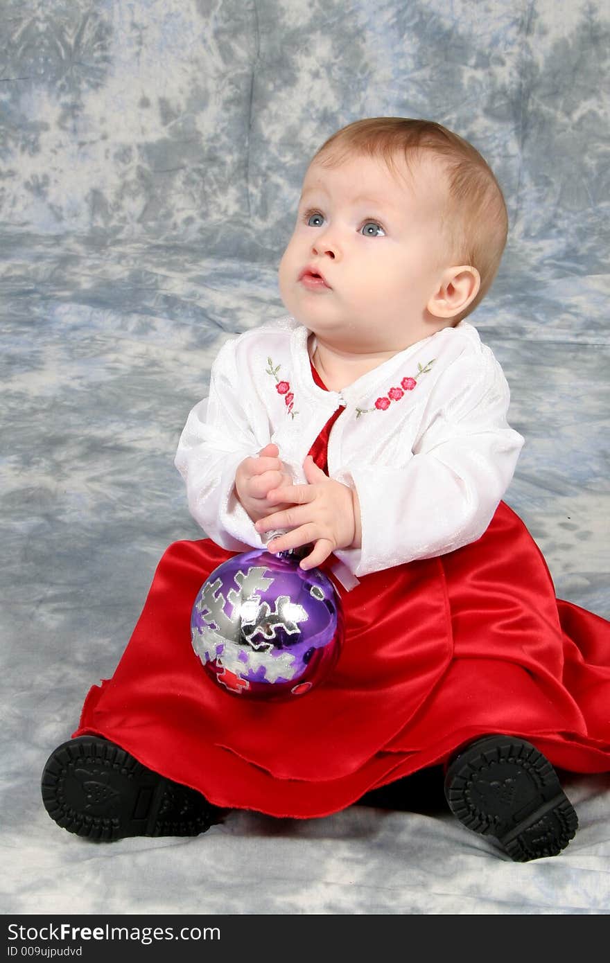 Little Baby Girl in Christmas dress with bulb in hand