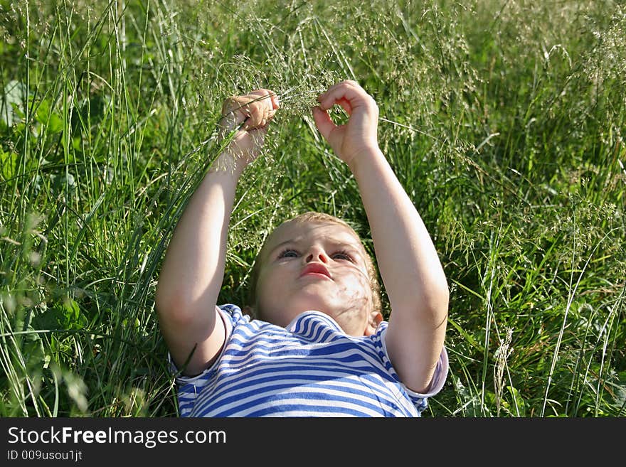 Kid head with hands lies on grass. Kid head with hands lies on grass