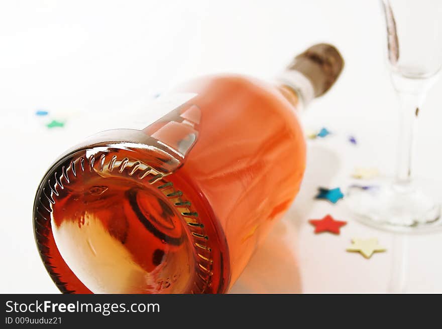 Pink champagne bottle lying down with a champagne glass and some glitter. Pink champagne bottle lying down with a champagne glass and some glitter