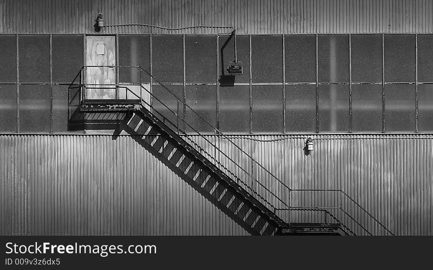 Black and white outside stairs, made from metal and leading to a rusty door.