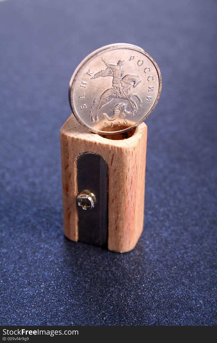 The Russian coin on a sharpener for pencils made of wood on a color paper