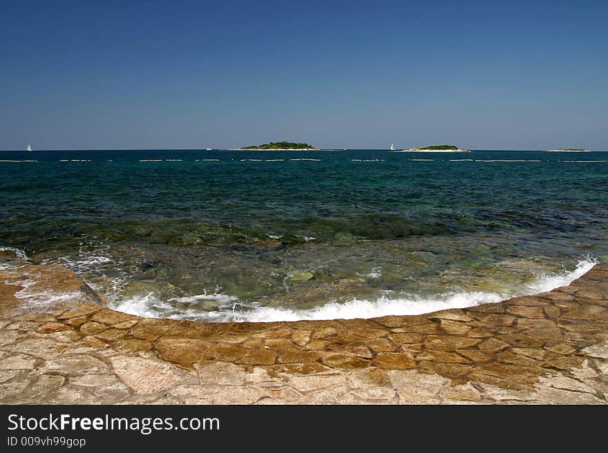 Wave bashing on sore with islands in the background. Wave bashing on sore with islands in the background