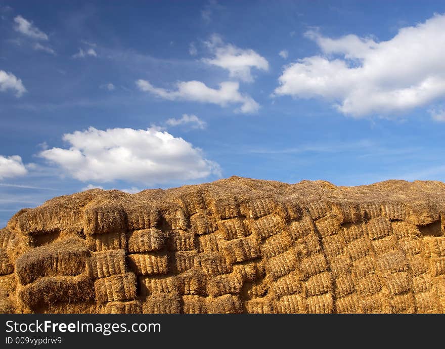 Wall of hay bales against a blue sky