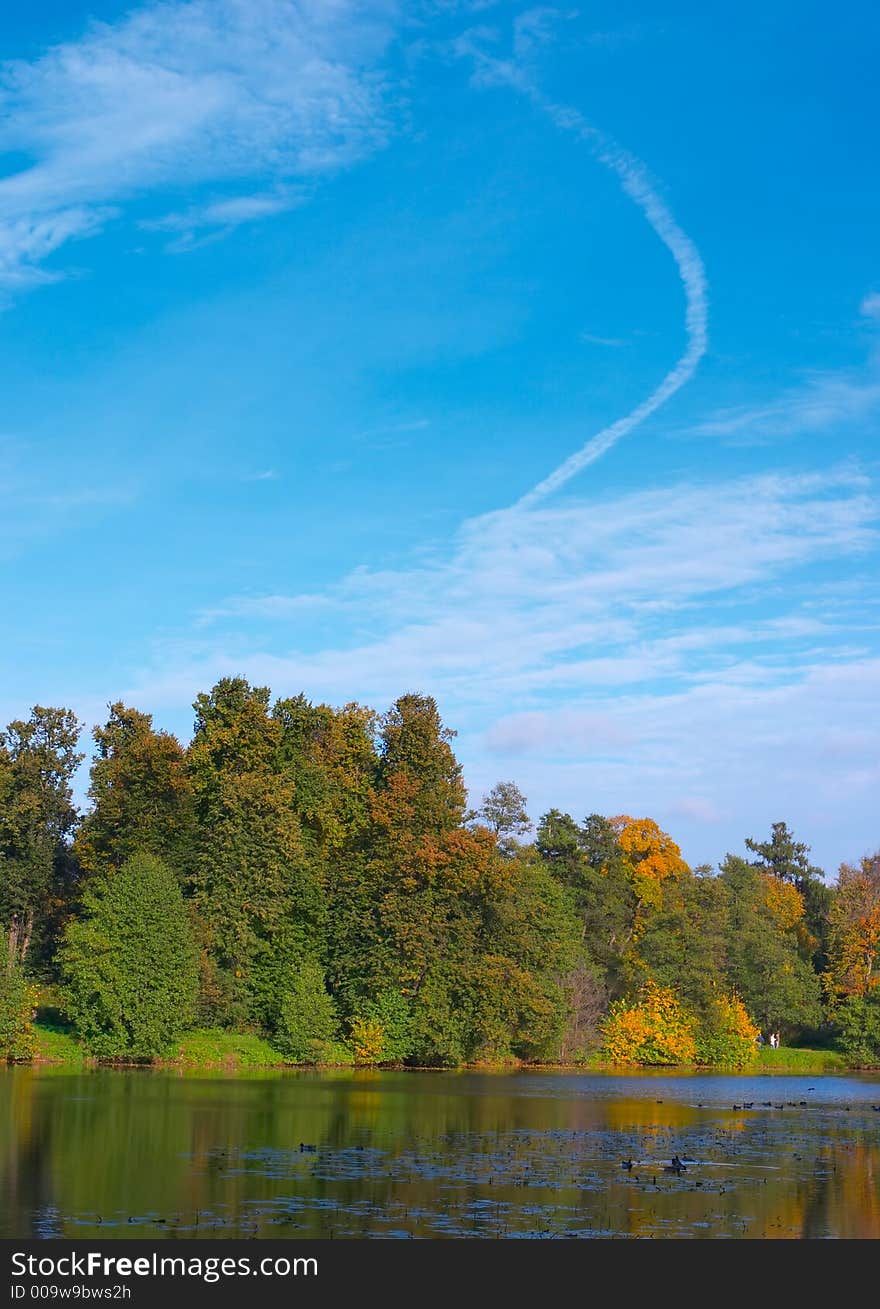 Coast of lake in an autumn wood and the sky with clouds