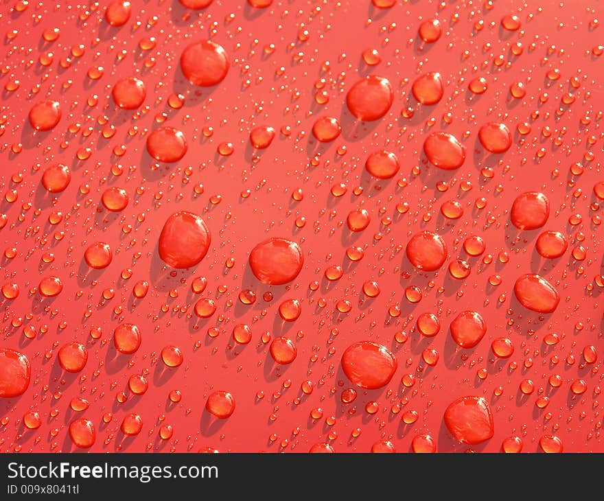 Rain droplets formed on red metallic surface