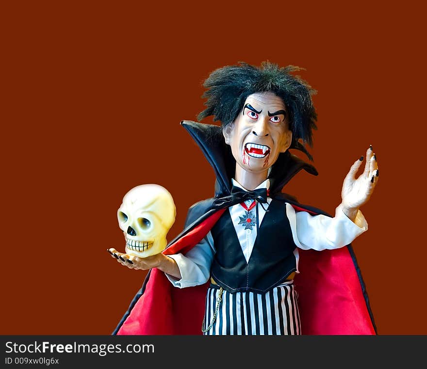 Halloween doll dressed up as of a vampire holding a skull - isolated. Halloween doll dressed up as of a vampire holding a skull - isolated