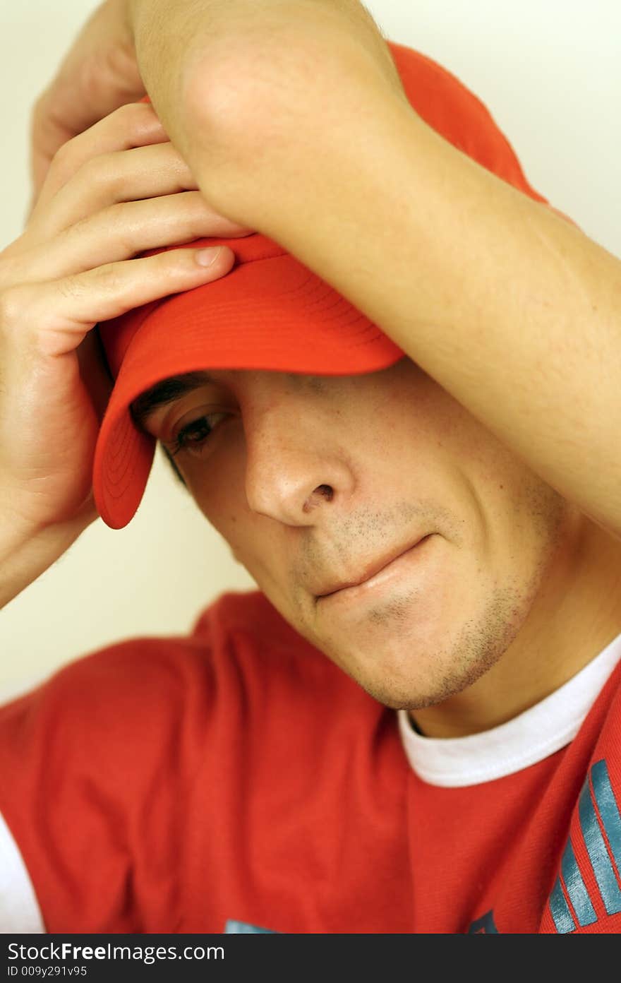 A young man with a red hat looking down. A young man with a red hat looking down