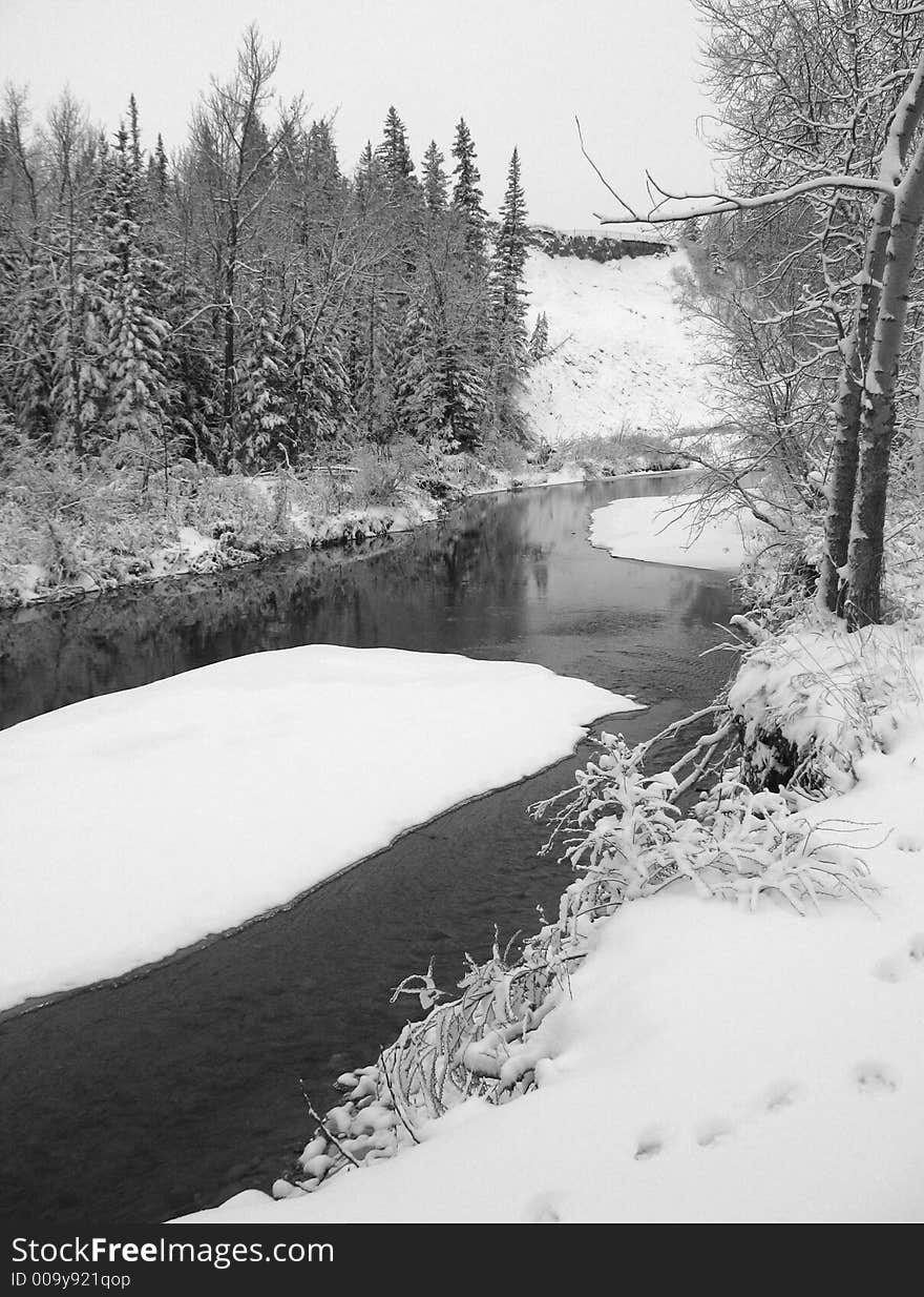 A part-frozen river meanders through a snowy landscape. A part-frozen river meanders through a snowy landscape.