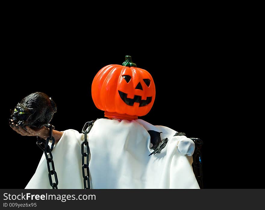 A pumpkin, jack-o-lanten headed Halloween doll made up to look like a ghost and holding a huge rat, isolated on a black background. A pumpkin, jack-o-lanten headed Halloween doll made up to look like a ghost and holding a huge rat, isolated on a black background.