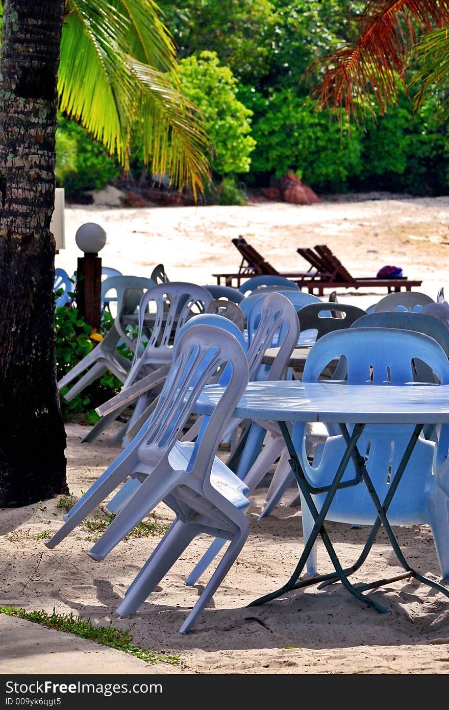 Plastic tables & chairs by the beach for dining at night.