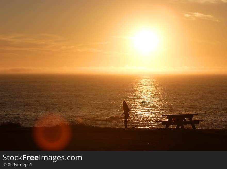 A girl walks along the sea cliffs at sunset. A girl walks along the sea cliffs at sunset