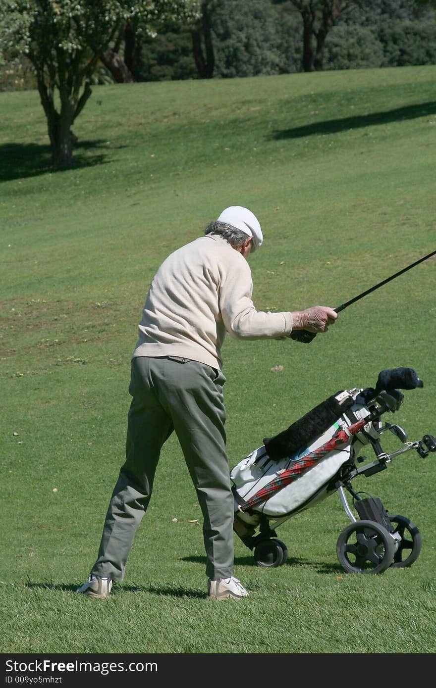 Old golfer and his cart on the fairway. Old golfer and his cart on the fairway