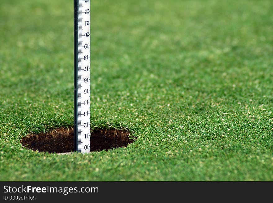 Green grass course, hole with white post. Green grass course, hole with white post